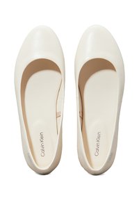 Bailarinas blancas de charol con punta redonda y diseño minimalista. Presentan una sutil marca en las plantillas. Textura suave.