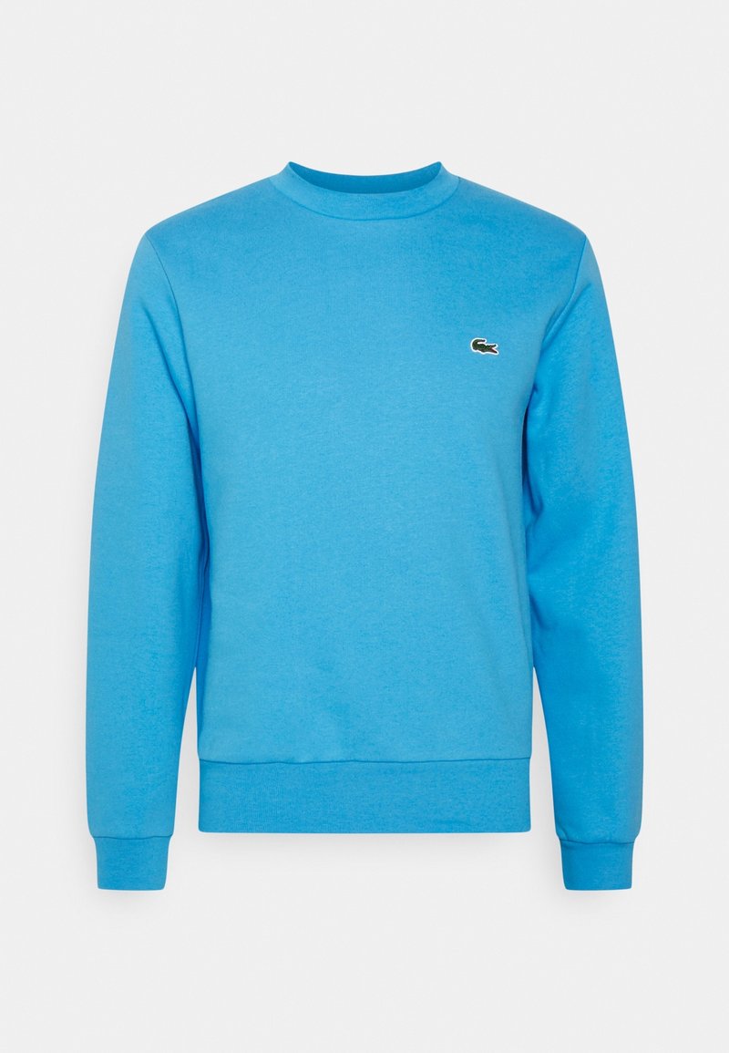 Sweatshirt bleu à manches longues avec col rond, poignets et ourlet côtelés, arborant un petit logo de crocodile vert sur la poitrine gauche.
