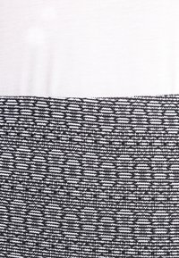 Zwart-wit patroonstof met een textuurachtig ontwerp, met horizontale lijnen en cirkelvormige accenten, samen met een gladde, witte tailleband.