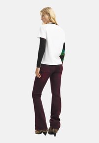 Valge lühikeste varrukatega särk musta pika varrukaga all, kokku sobitatud tumesiniste lõhikpükstega. Varrukatel värvikad mustrid ja jalanõud unikaalse disainiga.