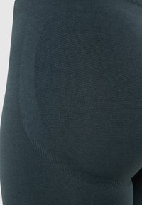 Donkerblauwe leggings met een gladde textuur, voorzien van een gevoerde naad aan de bovenbenen voor extra comfort en ondersteuning.