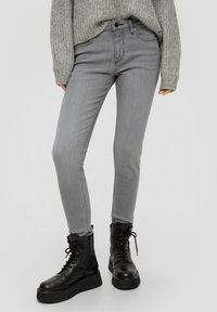 Grijze skinny jeans van denim, met een klassieke vijf-pocketdesign, gecombineerd met zwarte veterschoenen in combat-stijl.