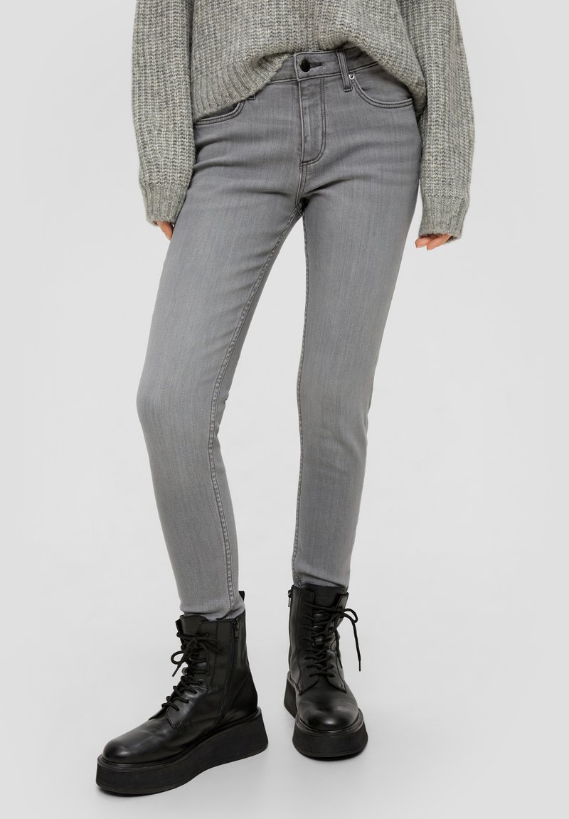 Grijze skinny jeans van denim, met een klassieke vijf-pocketdesign, gecombineerd met zwarte veterschoenen in combat-stijl.