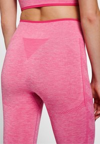 Růžové sportovní legíny z texturované, elastické látky. Na zádech mají trojúhelníkový designový prvek a vysoký pas.