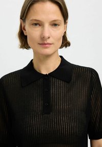 Svart skjorta med krage, ribbad textur, korta ärmar och fem svarta knappar. Tyget har en något genomskinlig känsla.