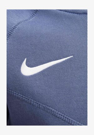 Sininen urheiluvaatekangas, jossa on sileä tekstuuri, sisältää hallitsevan valkoisen Nike-logon, jota korostavat vastakkaiset ompeluyksityiskohdat.