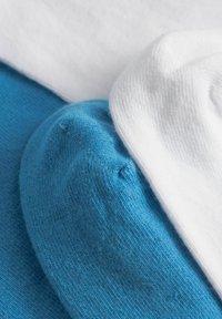 Gros plan sur des couches de tissu tricoté plié en bleu et blanc montrant la texture et les détails de couture.