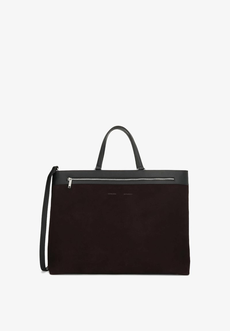 Grand sac fourre-tout noir avec des anses en cuir, une bandoulière amovible et une poche zippée horizontale près du haut.