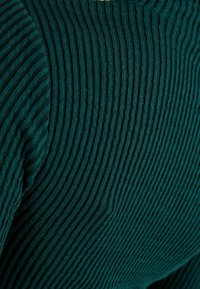 Tealfärgad ribbstickad tröja med vertikala linjer och mjuk textur, med rund halsringning och subtila sömdetaljer.