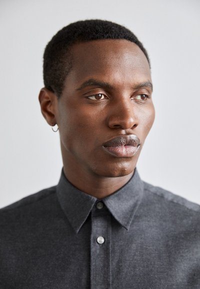 Dark gray button-up shirt with a collar, made of textured fabric; features a single button at the neck and an earring in the left ear.