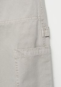 Tessuto grigio chiaro con una trama a coste, dotato di una tasca a toppa e dettagli di cucitura. Include un anello in tessuto sul lato per il fissaggio.