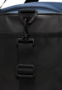 Bolsa de viaje negra y azul con una cremallera resistente, clip de plástico y tela de nylon texturizada, con una correa y detalle de hebilla de metal.