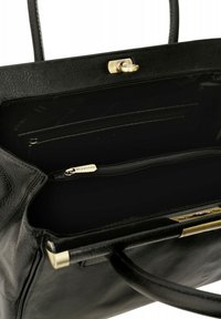 Interno di una borsa a tracolla in pelle nera con finitura testurizzata, dotato di una tasca con zip e hardware in tonalità dorata. Design minimalista e funzionale.