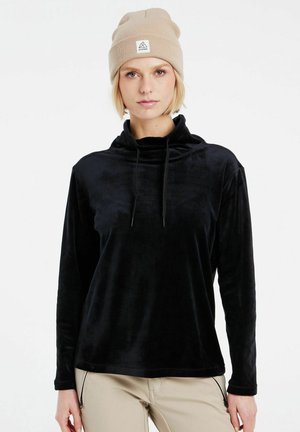 Pullover en polaire noir avec un col haut, des manches longues et des accents à cordon de serrage. Le modèle porte un bonnet en tricot beige avec un détail de logo.
