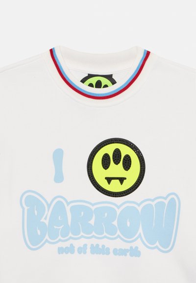 White cotton t-shirt featuring a ribbed neckline with red and blue stripes. Graphic design in blue and a black outline with a green smiley face detail.