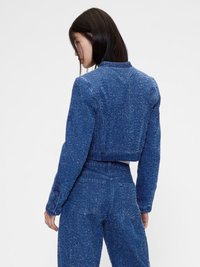 Jachetă din denim albastru, tăiată, cu țesătură texturată, manșete cu nasturi și croi drept. Dispune de detalii la cusătura din spate și guler.