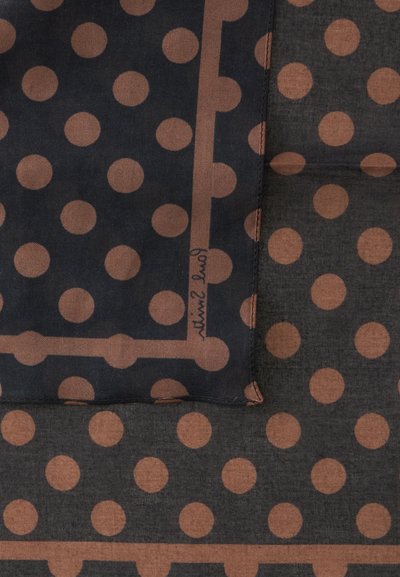 Tissu avec un motif de pois marron uniformément espacés sur des fonds gris foncé et noir, montrant une section pliée avec des coutures.