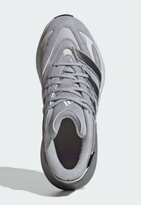 Gray athletic shoe with purple and black accents, featuring a textured upper, cushioned interior, and rubber sole with a rounded shape.