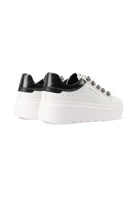 Sneakers platform bianchi con dettagli neri nel tallone e occhielli metallici esagonali, visti dal retro-destra.