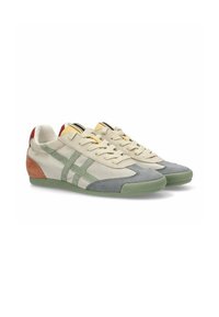 Zapatillas de deporte beige claro con acentos de ante verde y gris, laterales de malla transpirable y una suela de goma texturizada. Ojetes metálicos y forro amarillo.
