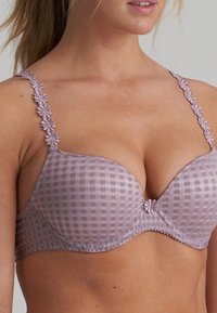 Lilafarbener karierter BH mit gepolsterten Cups, dekorativen Blumen-Trägern und gewelltem Rand. Mit einem mittigen Schleifchen als zusätzlichem Akzent.