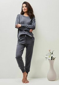 Graues Loungewear-Set mit einem lockeren Langarmoberteil und taillierten Hosen mit elastischem Bund. Weiche Textur, lässige Passform, minimalistisches Design.