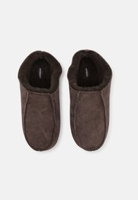 Pantoufles en daim marron avec un design à bout rond, une doublure intérieure douce et des coutures contrastantes le long des bords.