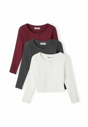 Trois hauts en maille côtelée à manches longues avec boutons au niveau du col en blanc, gris foncé et bordeaux, empilés verticalement sur un fond blanc.