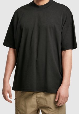 Sort T-shirt med korte ærmer lavet af bomuld, med rund halsudskæring og afslappet pasform, kombineret med lyse khaki bukser.