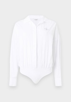 Hvit langermet bodysuit med krage, som har en innsvingt midje og en liten logo med dekorasjoner på brystet.