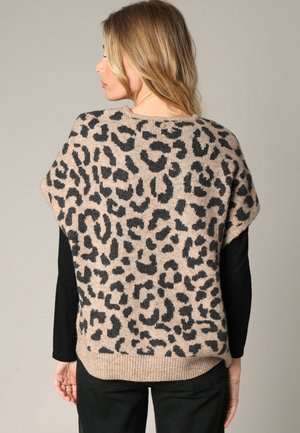 Pull marron avec un motif léopard noir, ourlet côtelé et larges manches courtes ; porté par-dessus un haut à manches longues noir.