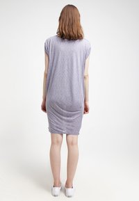 Abito a T-shirt di colore viola chiaro con una vestibilità morbida, maniche corte e un tessuto testurizzato. Il design presenta un orlo posteriore più lungo.