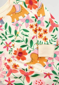 Tessuto soffice con vivaci stampe floreali e animali in rosa, arancio, verde e blu su uno sfondo color crema.