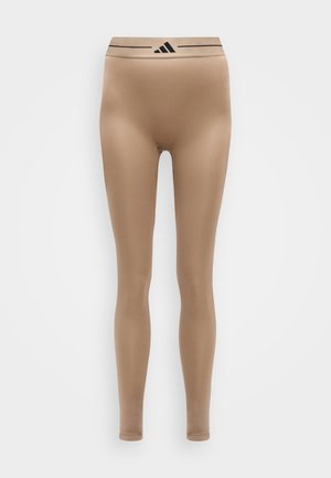 Μπεζ αθλητικό κολάν ολόκληρου μήκους με μαύρο λογότυπο Adidas στη μέση, παρουσιάζεται σε ανοιχτό φόντο.