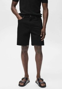 Zwarte denim shorts met een vijf-pocket ontwerp, metalen knoopsluiting en een rechte snit. Gemaakt om te dragen met zwarte sandalen, die een glad oppervlak tonen.