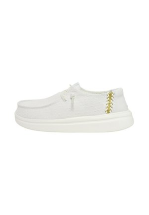 Baskets en toile blanche avec une tige texturée, un nez arrondi et un détail de couture dorée contrastante sur le talon. Semelle en caoutchouc blanche.