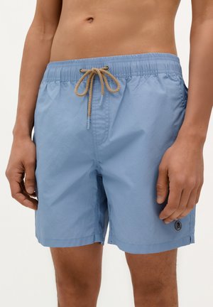Bañador de color azul cielo fabricado en tejido ligero. Presenta una cinturilla elástica con un cordón de color beige y un pequeño detalle con el logo en el dobladillo.