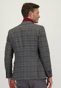 Grijze geruite blazer met een bordeauxrode kraag. Heeft een getailleerde pasvorm, twee knopen en een gestructureerde stof voor extra detail.