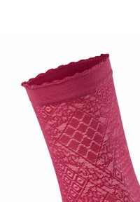 Calza rossa a fantasia con orlo ondulato, design testurizzato che presenta forme geometriche, realizzata con un materiale morbido e elasticizzato.