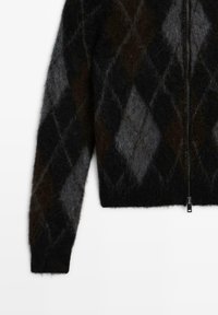 Pull à fermeture éclair noir et gris, duveteux, avec motif losanges argyle et manches longues, montré de face sur fond blanc.