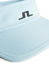 Ljusblå skärm med en slät textur, med en svart logotyp och stickade detaljer längs brätten. Justerbar passform.