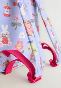 Sac à dos enfant violet clair avec bretelles rouges et imprimés cartoon d’animaux, fruits et fleurs sur le tissu.