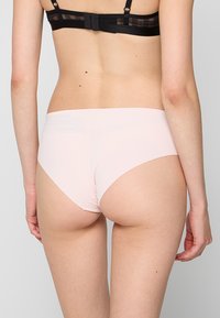 Braguitas sin costuras de color rosa claro con una textura suave y diseño de corte alto, con una cinturilla mínima y sin costuras visibles.