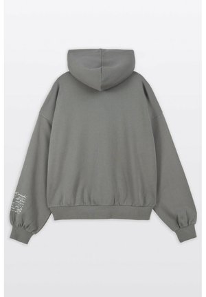 Szara bluza z kapturem o luźnym kroju, z elastycznymi mankietami i ściągaczem na dole. Z napisem na lewym rękawie w kontrastującym kolorze.