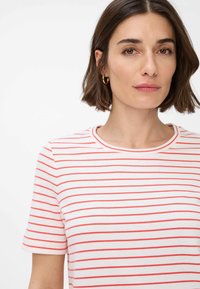 Witte t-shirt met korte mouwen, voorzien van horizontale rode strepen, ronde halslijn en een zachte textuur. Geaccentueerd met een getailleerd ontwerp.