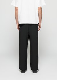 Calças largas pretas, com uma textura suave, cintura alta e bolsos laterais. Combinadas com uma t-shirt oversized branca simples.