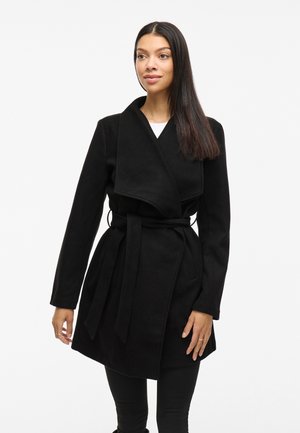 Cappotto avvolgente nero realizzato in tessuto morbido, con ampio colletto, maniche lunghe e vita con cintura, che conferisce una silhouette strutturata.