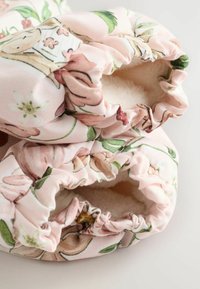 Lillelise mustriga kangast saabastega roosa taustaga, millel on volangidega ääred ja pehme, kohev vooder. Kaunistatud erinevate lillemustrite ja roheliste detailidega.