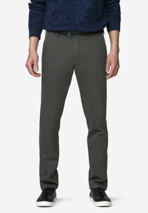 Mann trägt dunkelgraue Hose mit geradem Bein, ein marineblau gemustertes Langarmhemd und schwarze Sneakers mit weißen Sohlen.