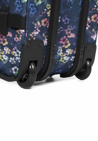 Rolkoffer met een marineblauwe achtergrond en een bloemenpatroon in roze, geel en wit; stevige zwarte wielen en accenten.